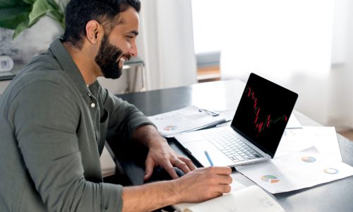 Smart concentrated indian successful broker investor, uses laptop to analyze financial cryptocurrency market, invest in e-currency, buy or sell crypto coins, analyze financial data, develop strategy